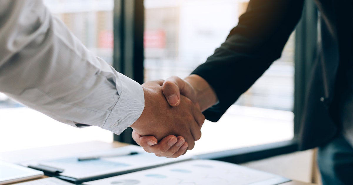 Business professionals shaking hands after successful meeting, showing agreement and partnership in office setting