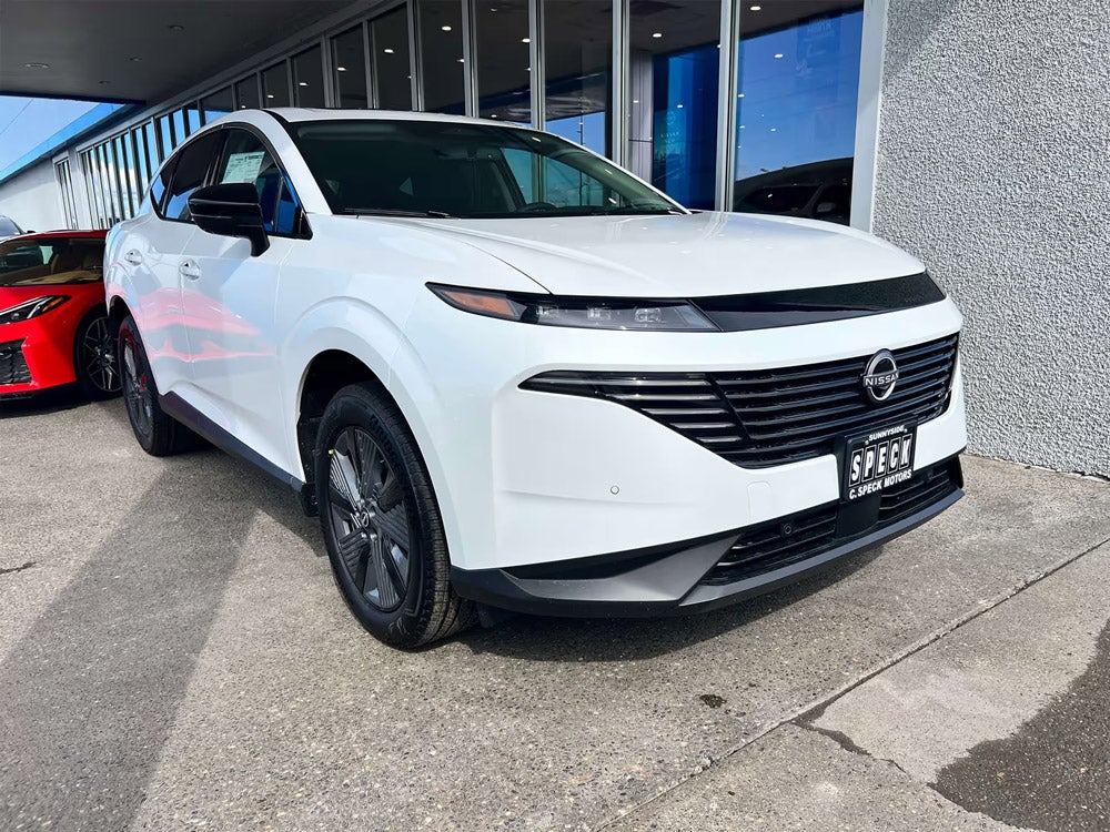 White Nissan SUV with sleek design parked at dealership, featuring modern grille and black accents