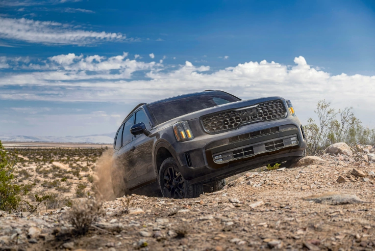 dark blue kia telluride driving up a rocky hill