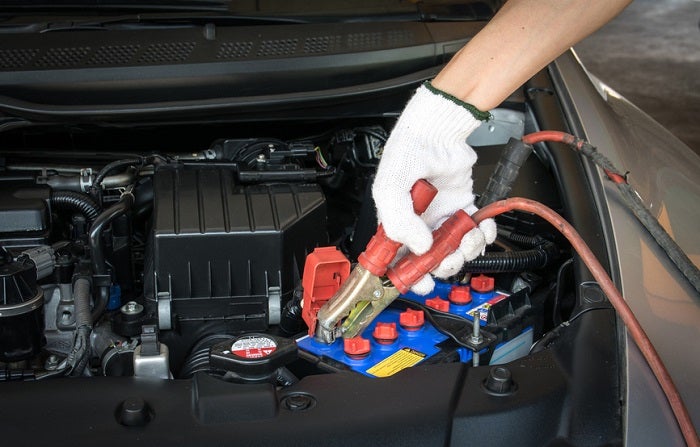 automotive technician charging vehicle battery