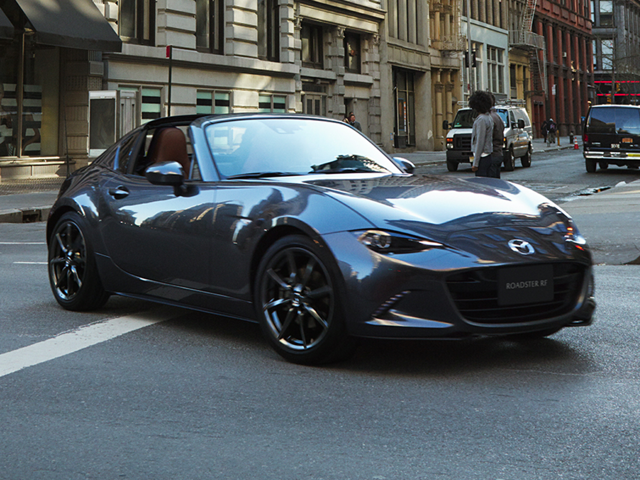 A Mazda Miata MX5 on the street next to a building