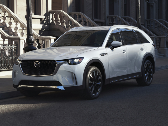 A white Mazda CX-90 PHEV parked next to a building