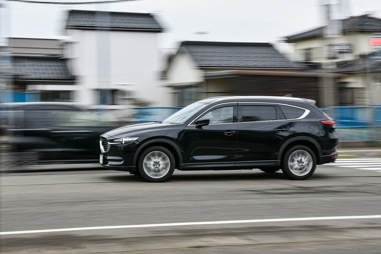 A Mazda SUV driving fast on a road