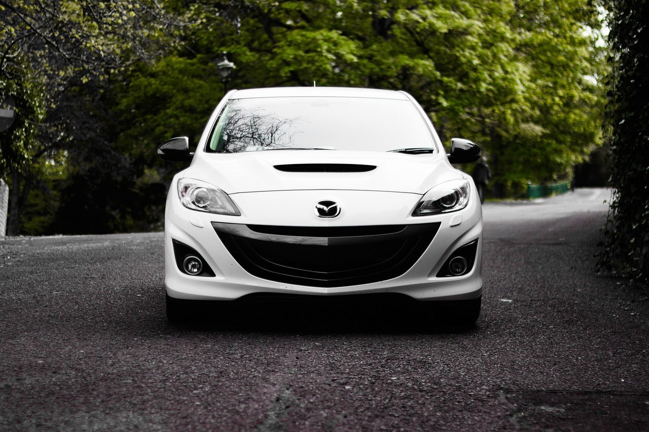 A white Mazda car parked outside