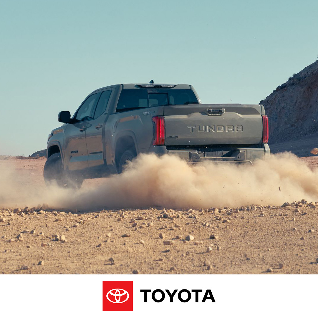 Gray Toyota Tundra truck kicks up a cloud of dust while driving off-road in a desert landscape.