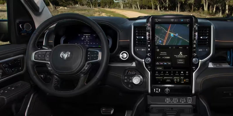 Interior view of a Ram truck showing the steering wheel, digital instrument cluster, and large central touchscreen with navigation and controls