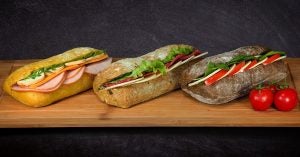 3 sandwiches on a wooden platter