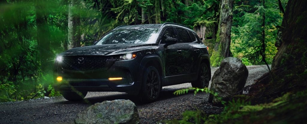 Mazda CX-50 SUV navigating a scenic wooded road in Louisiana-style outdoor terrain