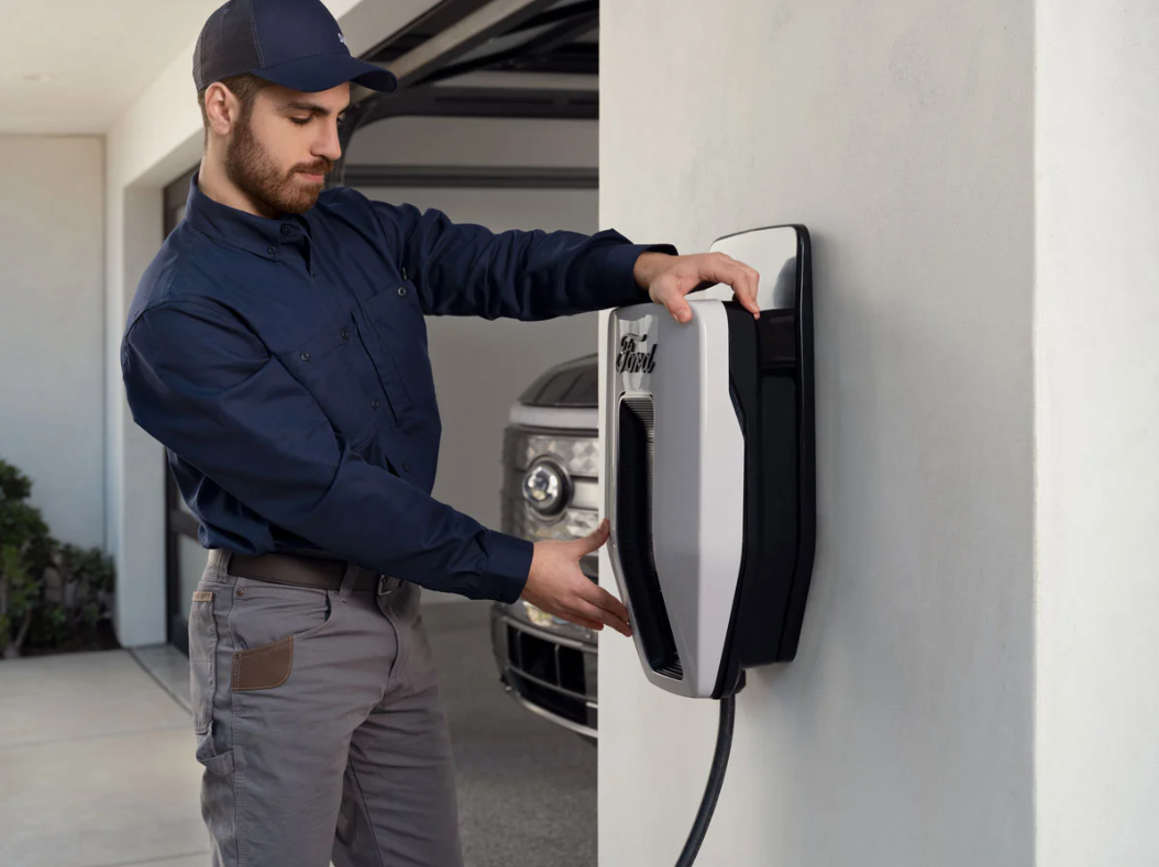 A technician connects an electric vehicle charger to a wall.