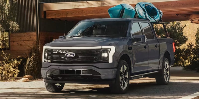 A Ford F-150 with kayaks on the roof, parked in a driveway.