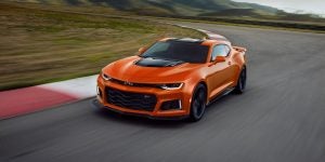 An orange camaro driving around a racetrack