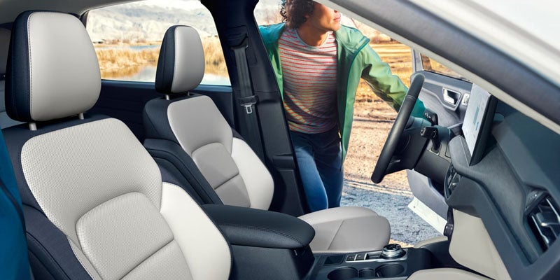 A modern car interior with premium seats, as a person enters from the driver’s side door.