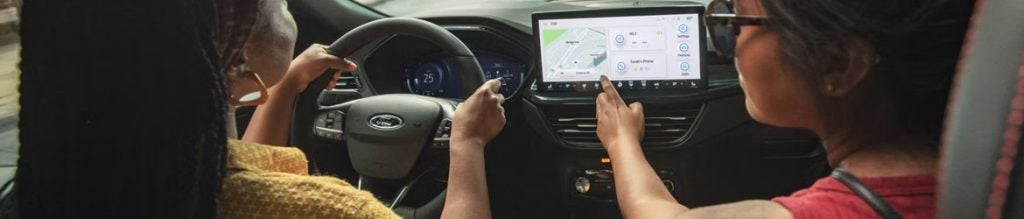 Driving scene with person using touchscreen navigation inside a car.