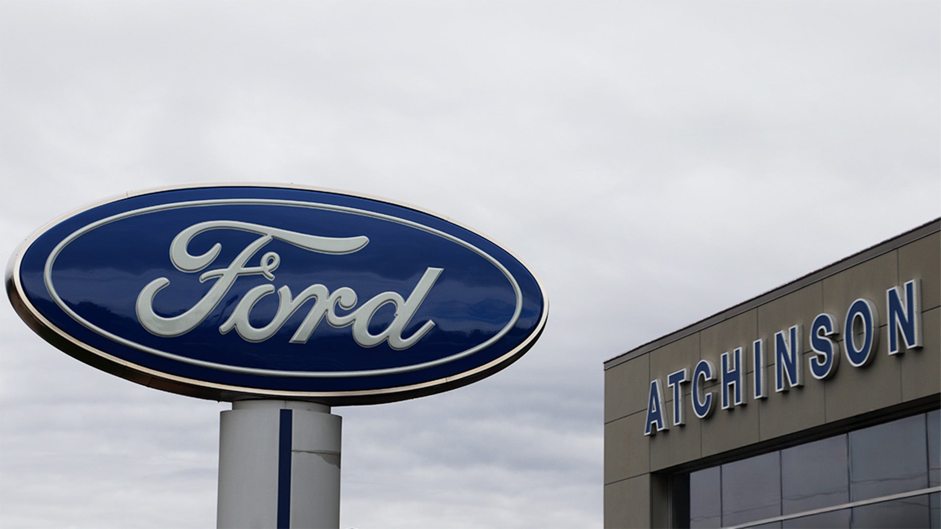 Ford oval sign beside the Atchinson Ford dealership building in Belleville, Michigan