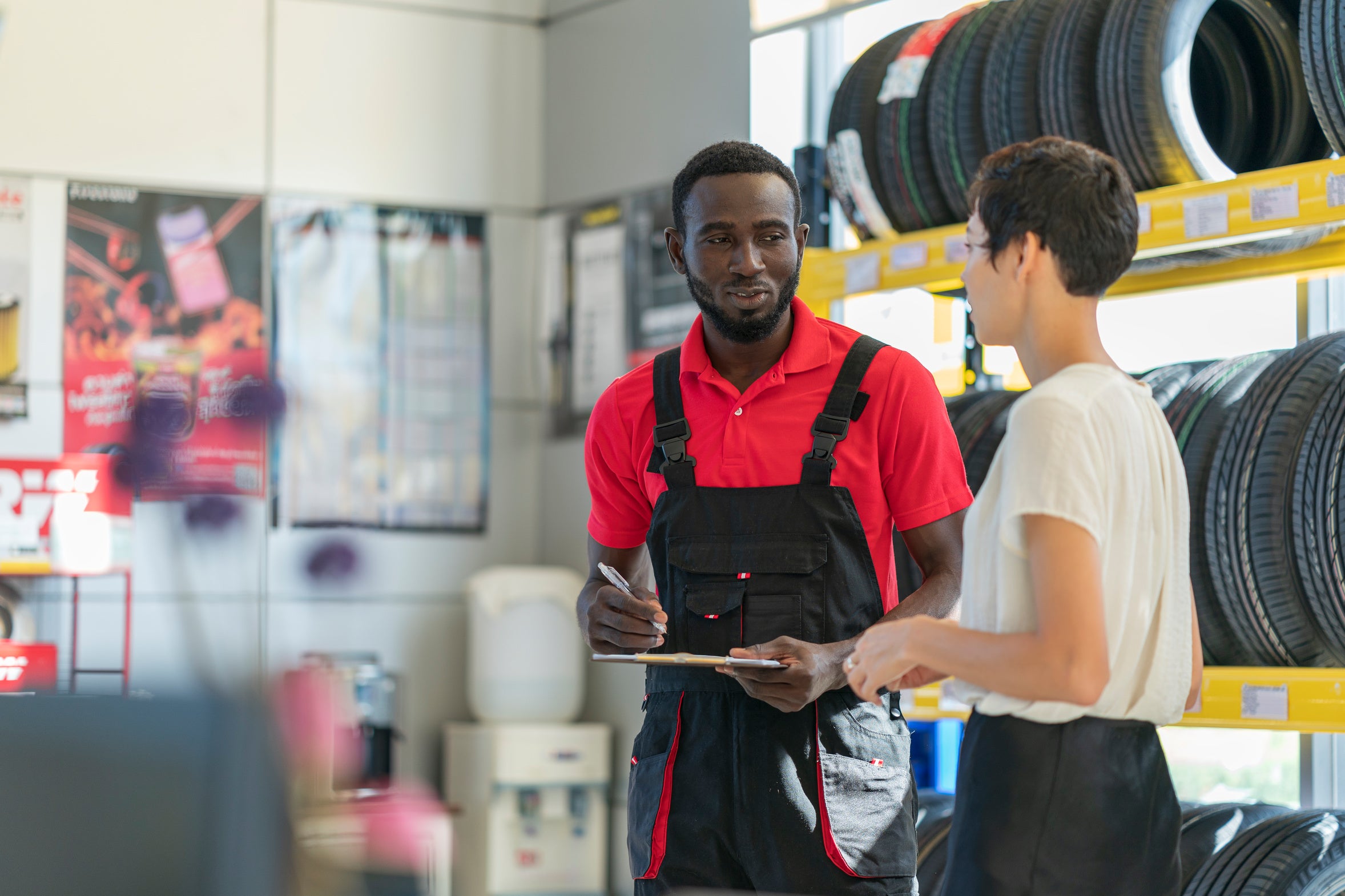 A tire-service professional reviewing paperwork with a customer