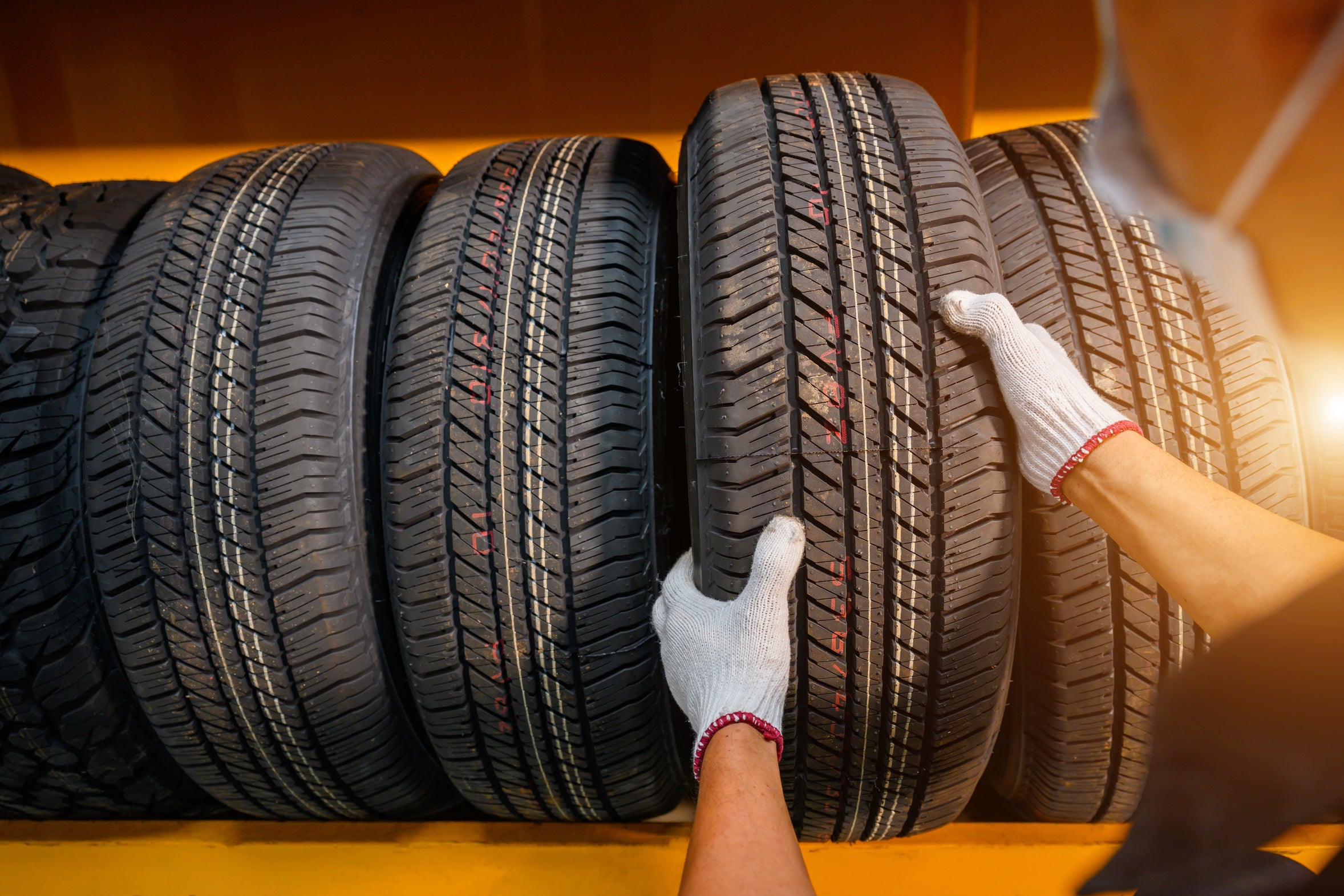 Gloved hands inspecting a row of vehicle tires