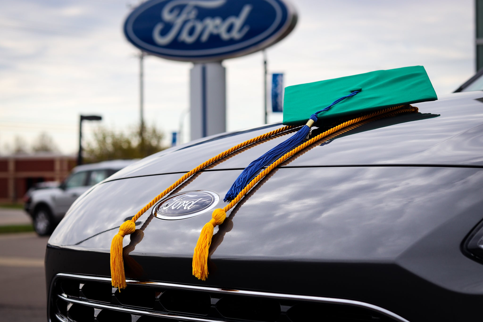 Graduation cap resting on the hood of a Ford vehicle