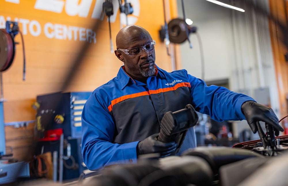 Quick Lane technician inspecting a vehicle’s engine