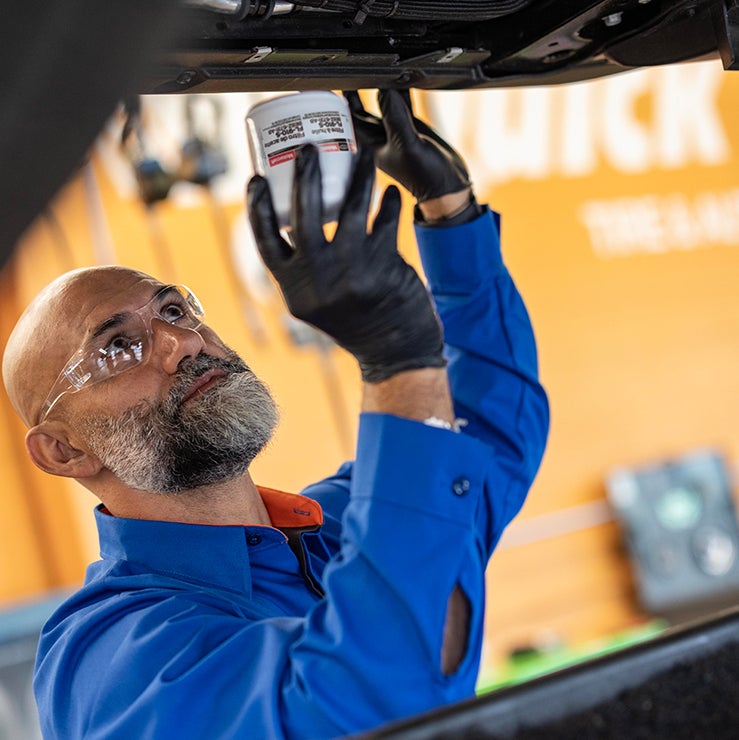 Quick Lane technician replacing a vehicle’s oil filter