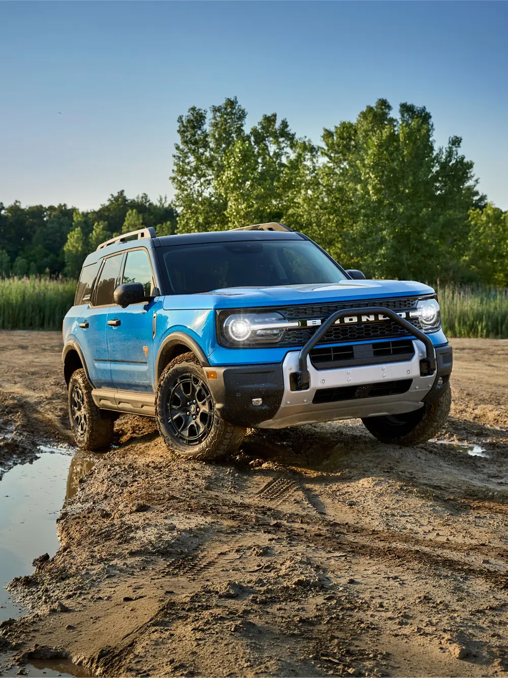 Blue 2026 Ford Bronco Sport Badlands with Sasquatch Package climbing a muddy riverbank trail