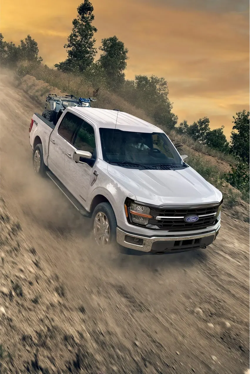 White 2026 Ford F-150 XLT kicking up dust on a rocky off-road trail