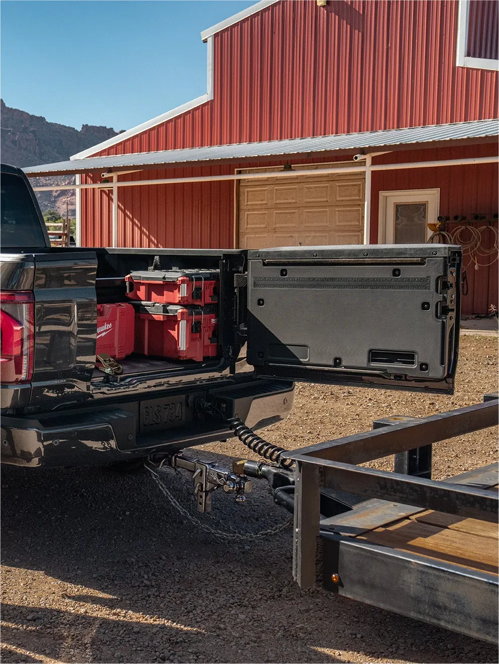 Ford F-150 Pro Access Tailgate open beside a red barn with a dirt bike in the bed