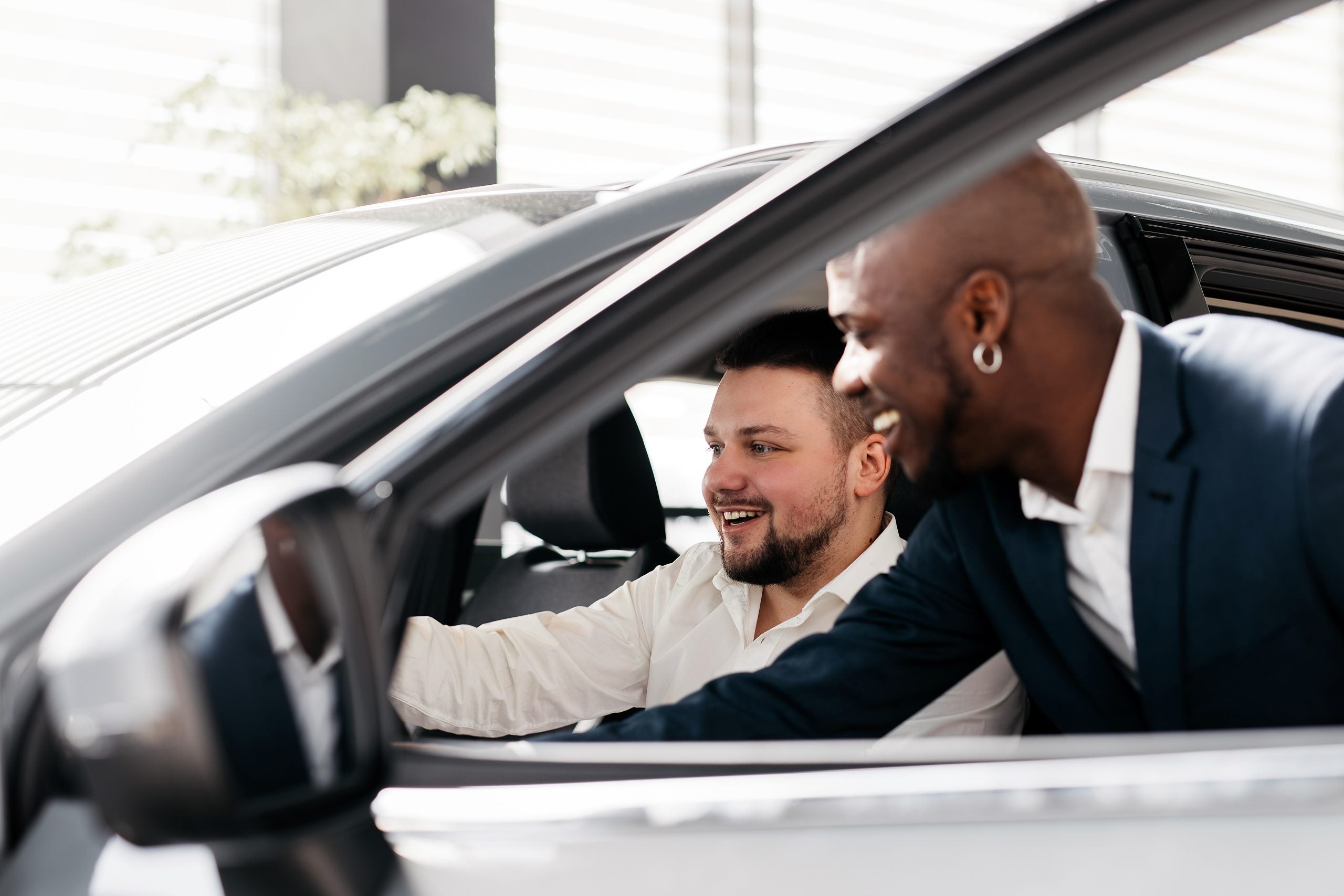 African-American dealer counseling a customer on buying a modern car at a car dealership.
