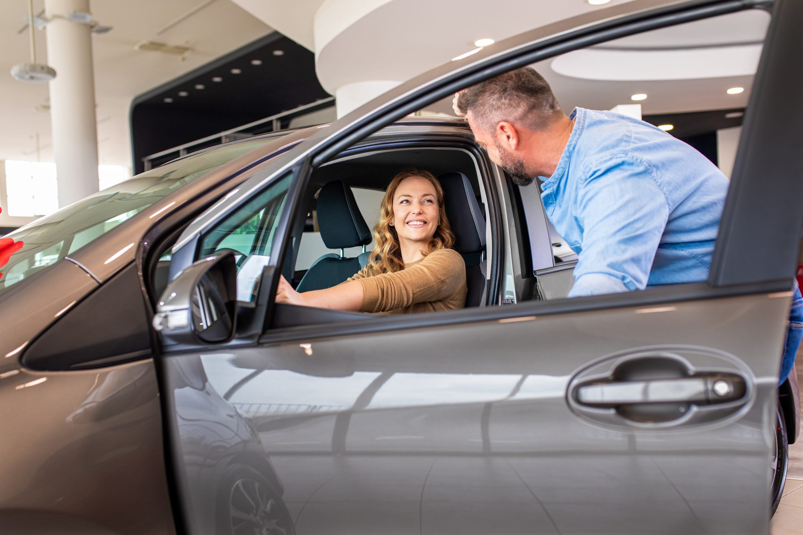 Smiling mid-adult couple buying a new car from dealership.