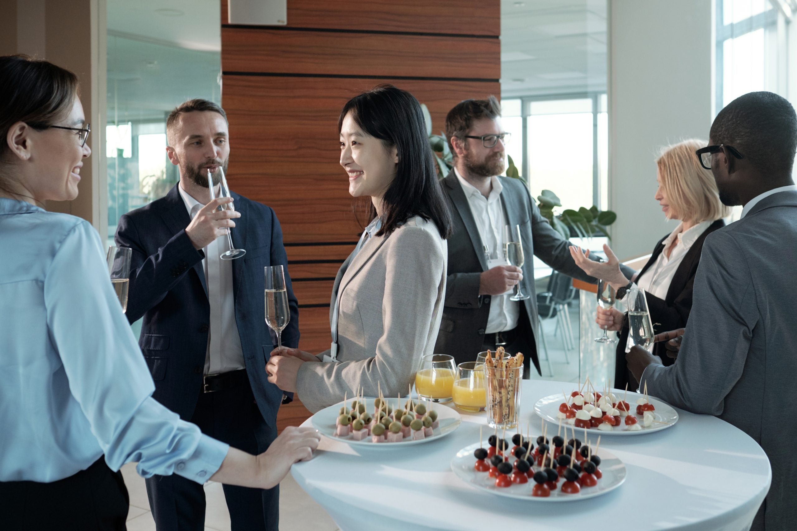 Three cheerful intercultural colleagues with champagne having discussion