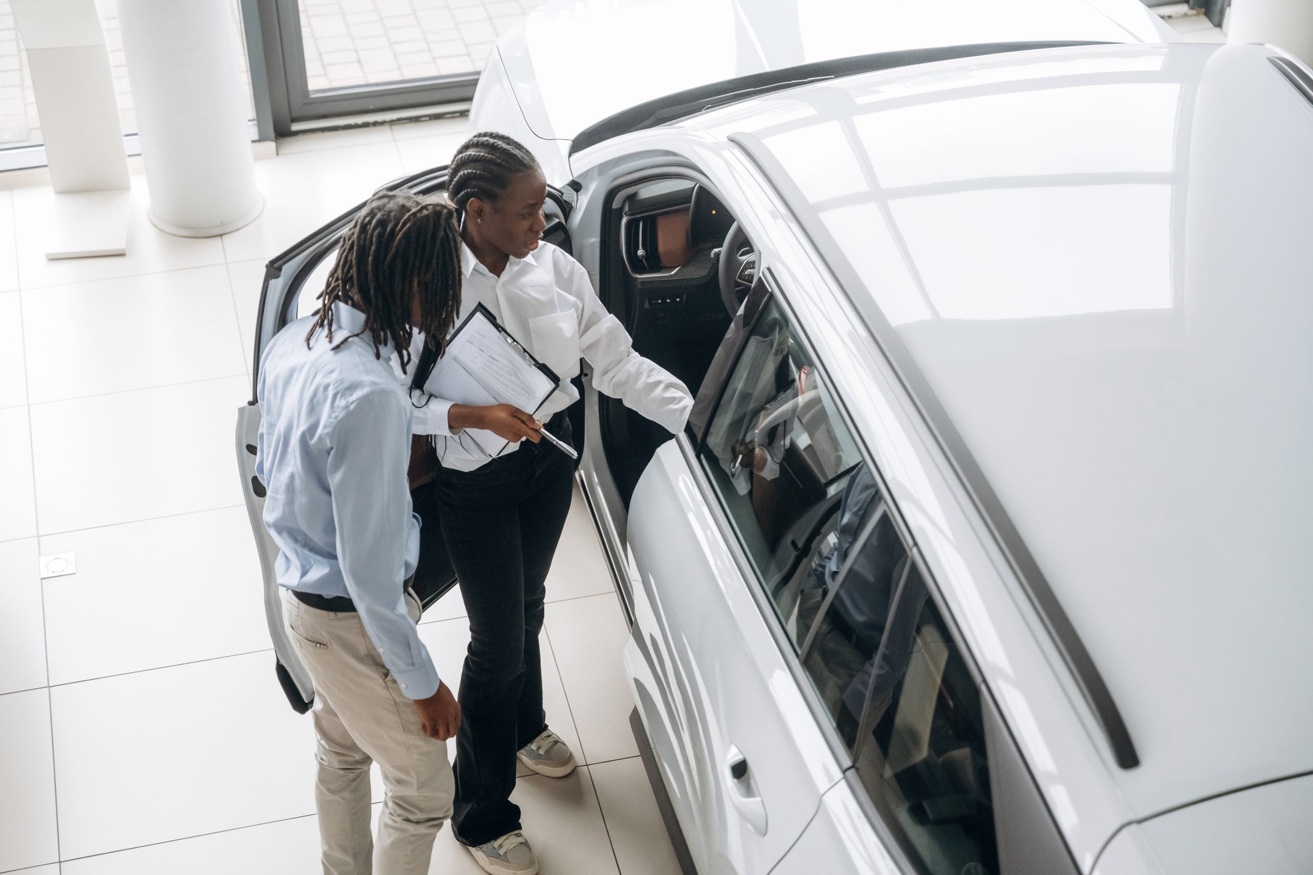 Female car seller is assisting client in the automobile salon