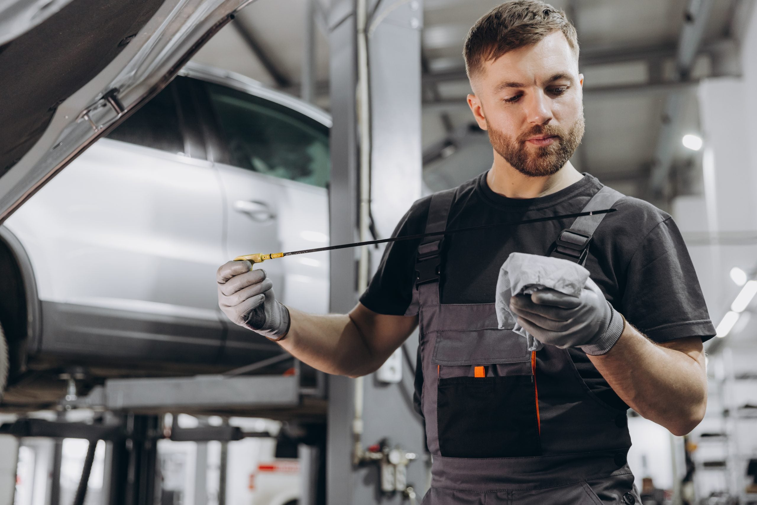 Car mechanic checking the engine oil level in the service center