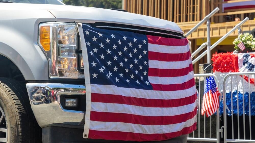 A truck with an American Flag tied to the bumper