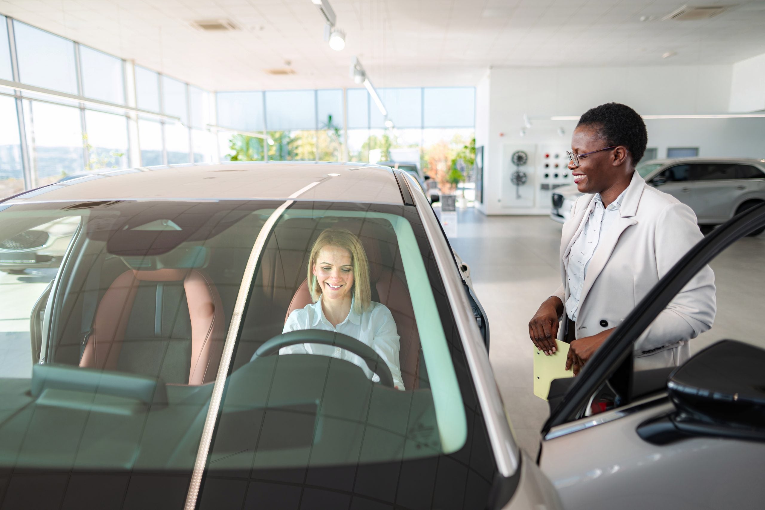 Woman buying new car with saleswoman at dealership
