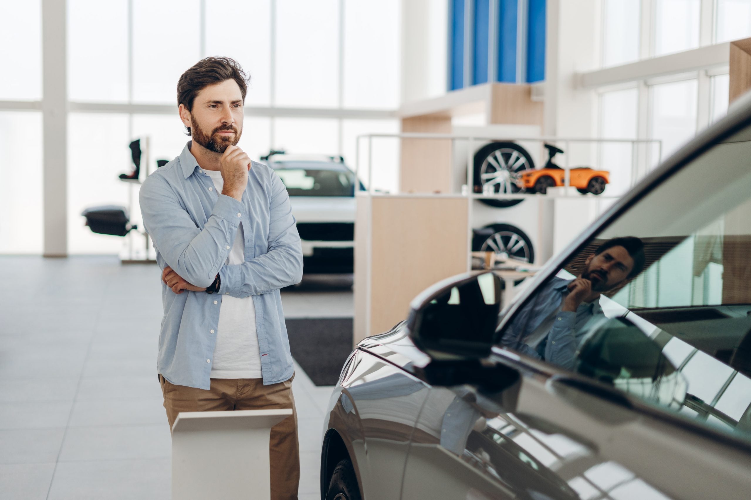 Customer choosing thinking about buying new car in dealership showroom