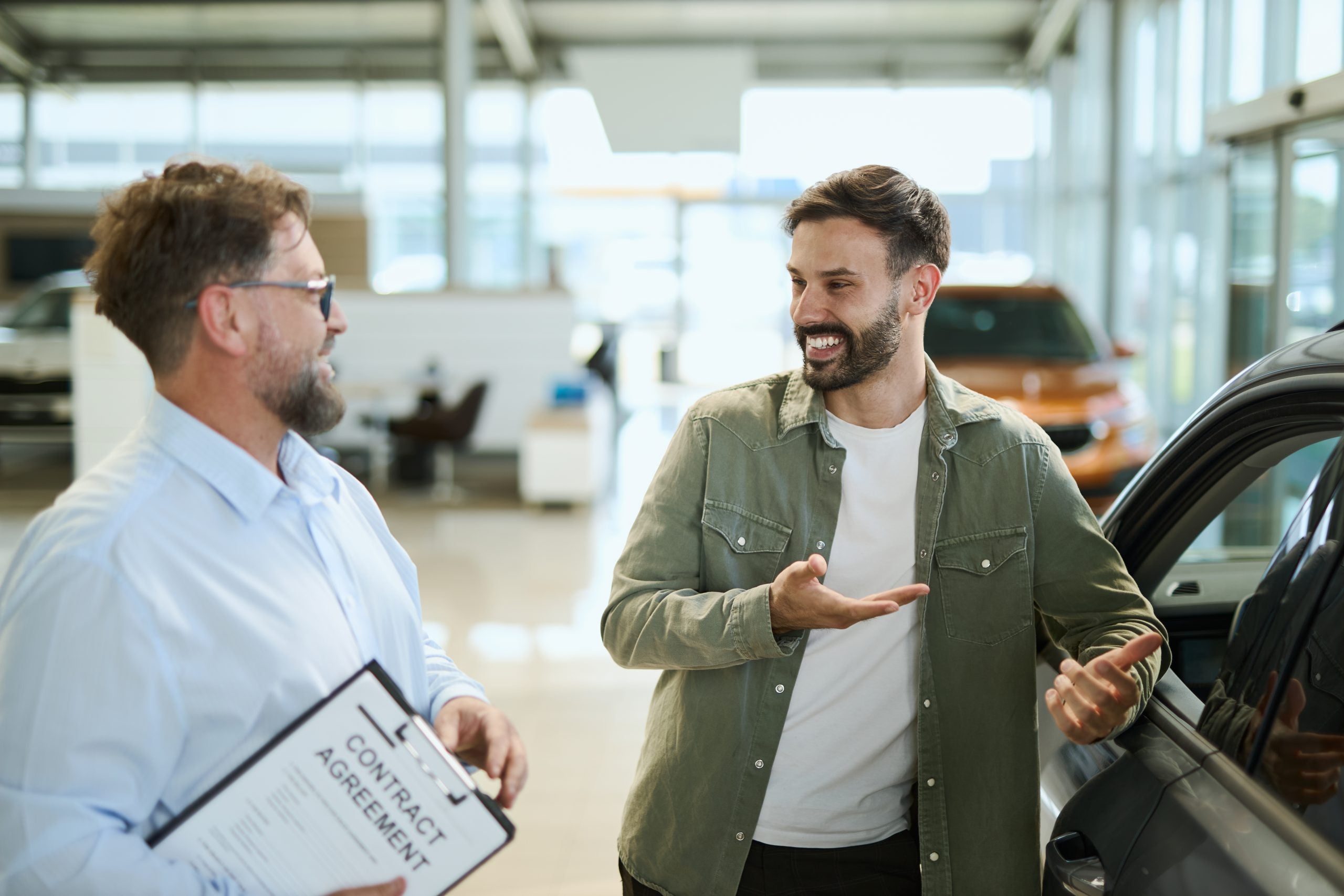 Male customer talking with salesman in a car showroom.