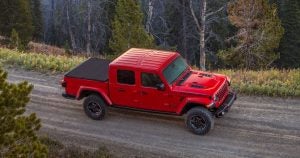 A red 2020 Jeep Gladiator driving on a dirt road through the hills near Sheboygan, WI