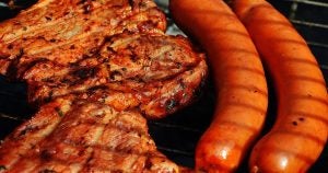 Two pork chops and two sausage links cooking on a barbecue grill in Port Washington, WI