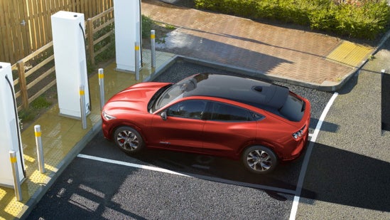 a red mustang is parked in an electric charging station 
