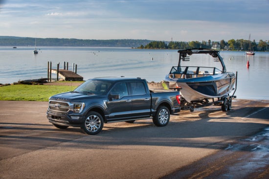 a grey ford f150 towing a car away from a lake 