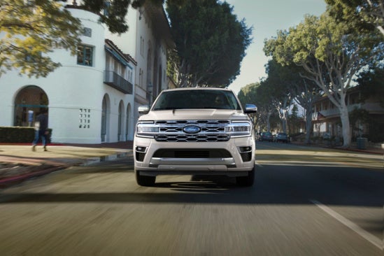2024 silver Ford Expedition SUV driving down a suburban road 