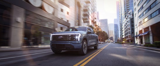 a silver ford f-150 driving down a city street 