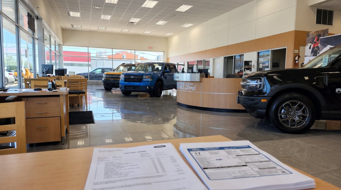A printed factory order and a Ford window sticker on a desk in the Nick Mayer Ford showroom