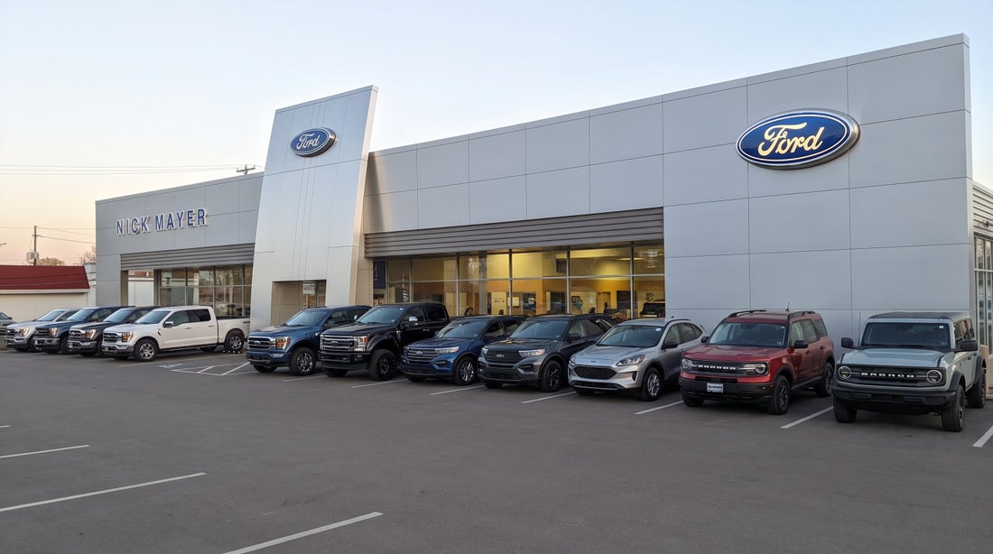 New Ford trucks and SUVs lined up outside the Nick Mayer Ford dealership at dusk