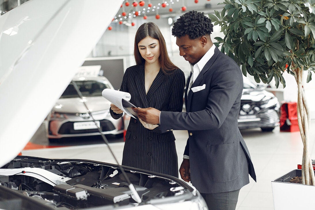 Looking at papers in front of a car