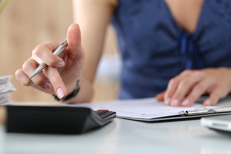 Person using a calculator and writing on documents.