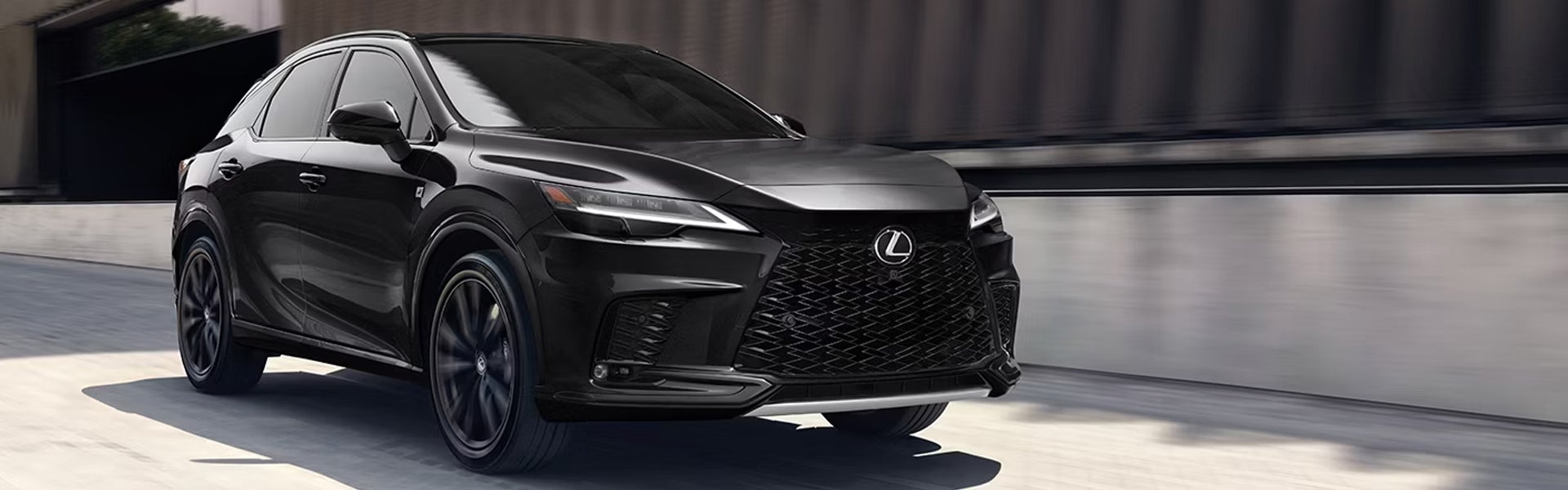 Black Lexus SUV driving on a city road.