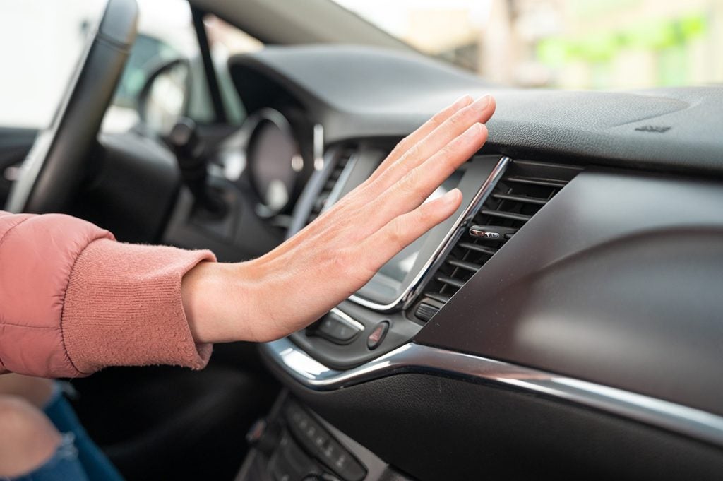 holding hand in front of AC in a car