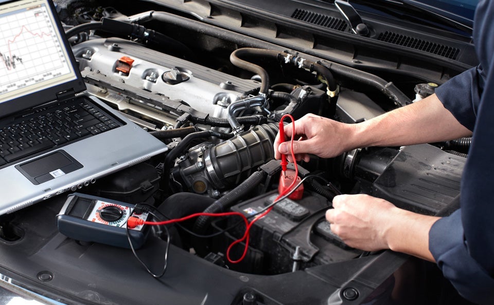mechanic testing battery of a car using his laptop 