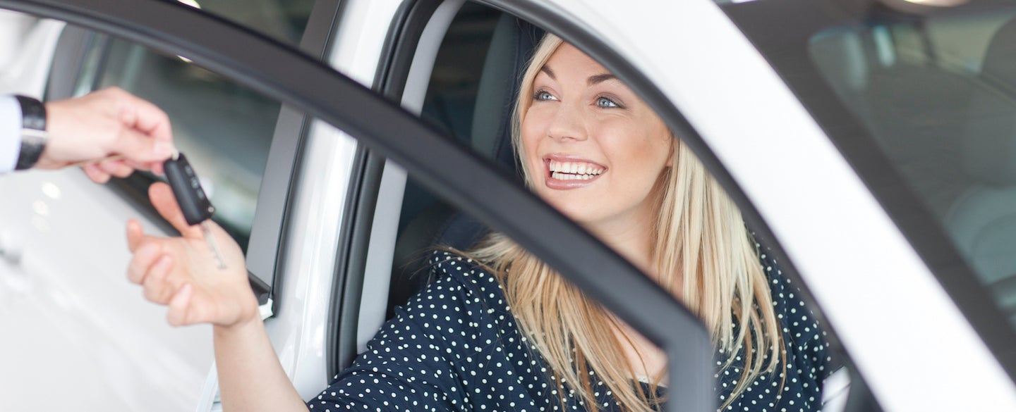 Young woman sitting in new car with key in Wallace showroom