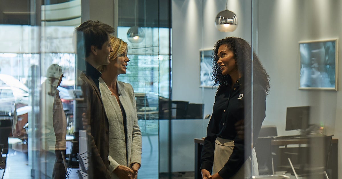 Customers speaking with salesperson at a Mazda dealership